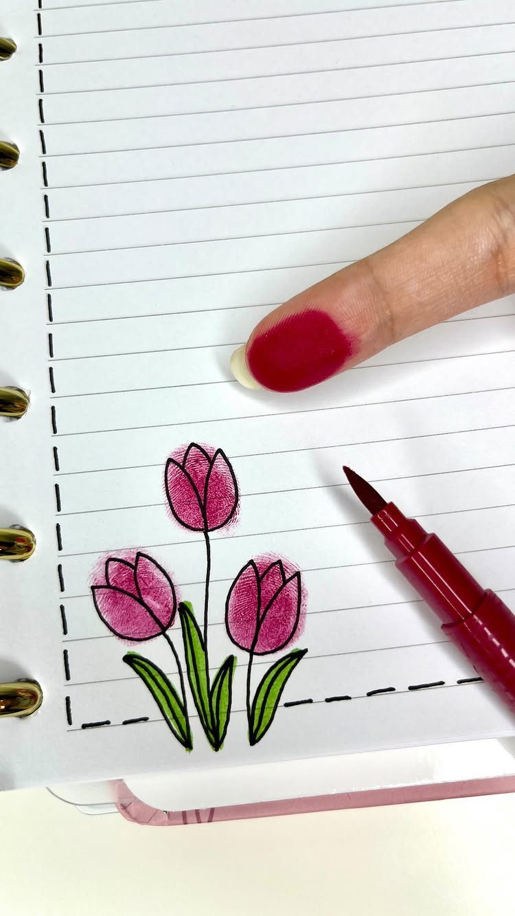 Fingerprint pink tulips with green stems drawn in a lined spiral notebook.