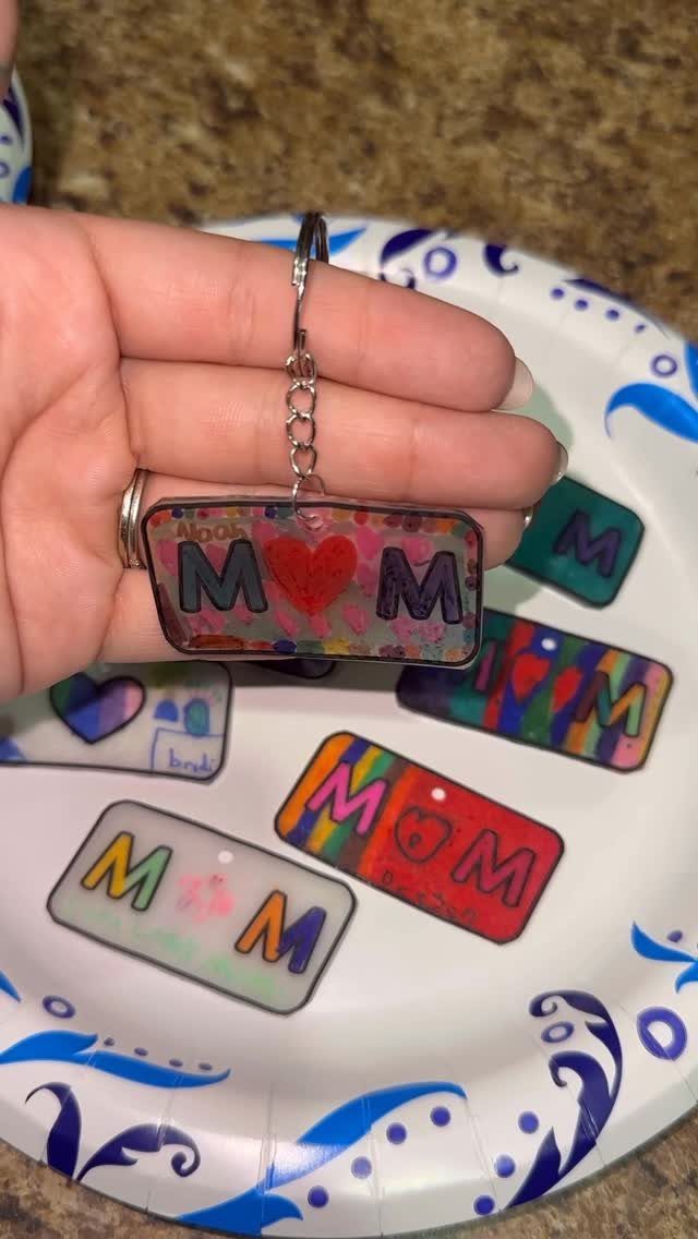 Handmade MOM keychains with colorful designs and hearts on a patterned paper plate