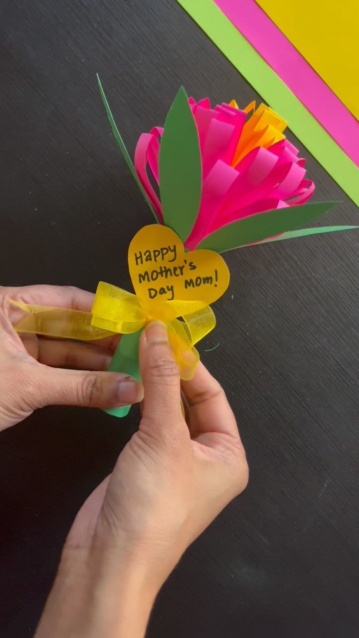 Handmade paper flower with pink petals and a yellow heart Mother's Day tag.