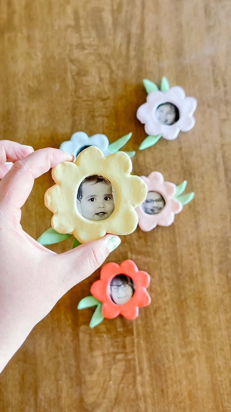 Yellow flower-shaped photo frame held by a hand over a wooden table.