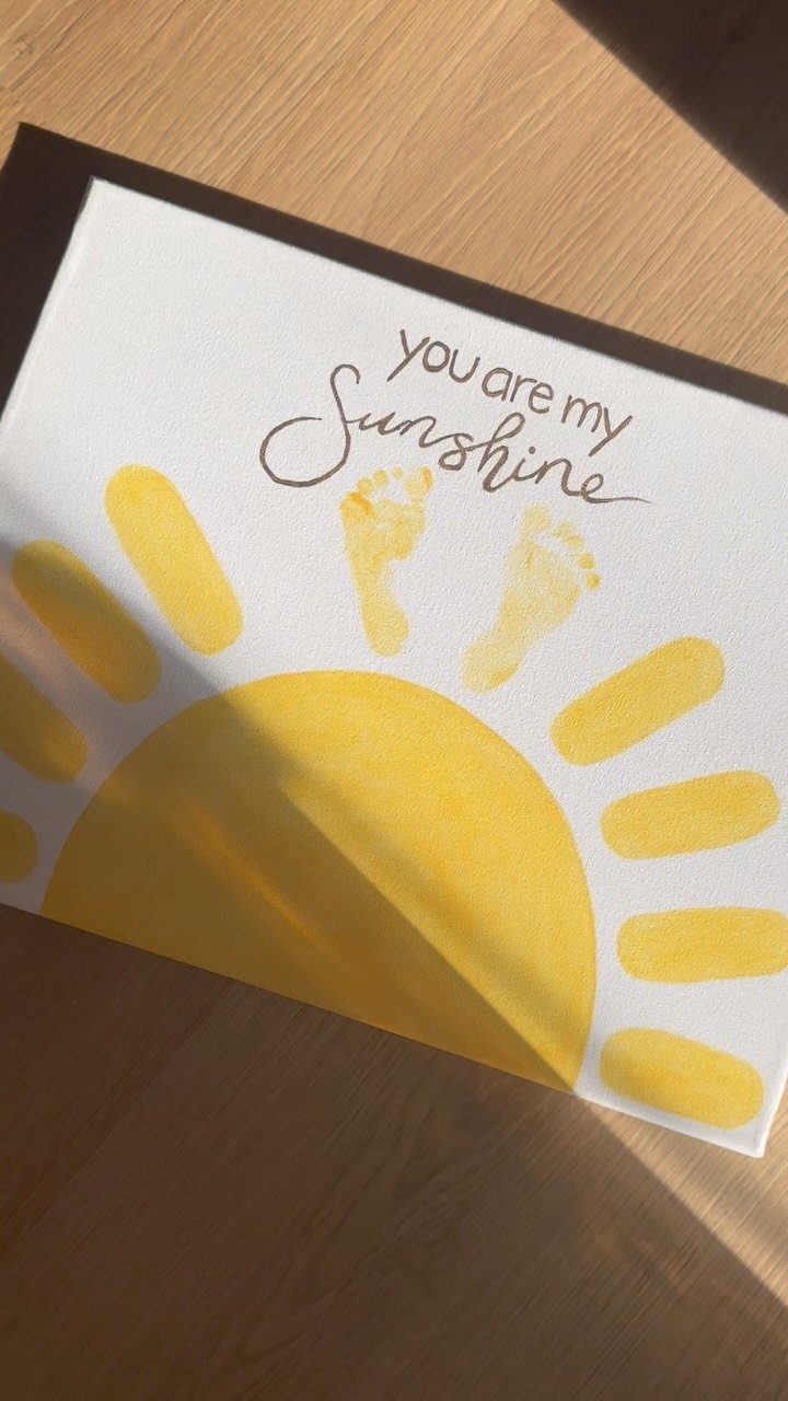Yellow painted sun and child footprints on white paper with handwritten sunshine text.