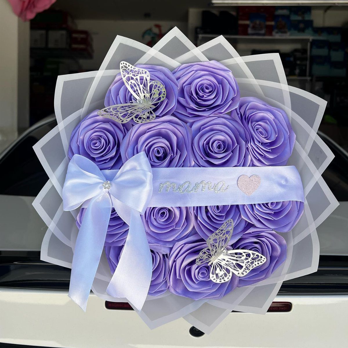Purple paper rose bouquet with silver butterflies and a light purple satin bow.