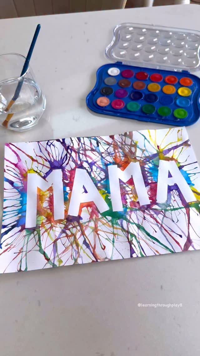 Colorful paint resist card with the word MAMA surrounded by vibrant paint splatters.