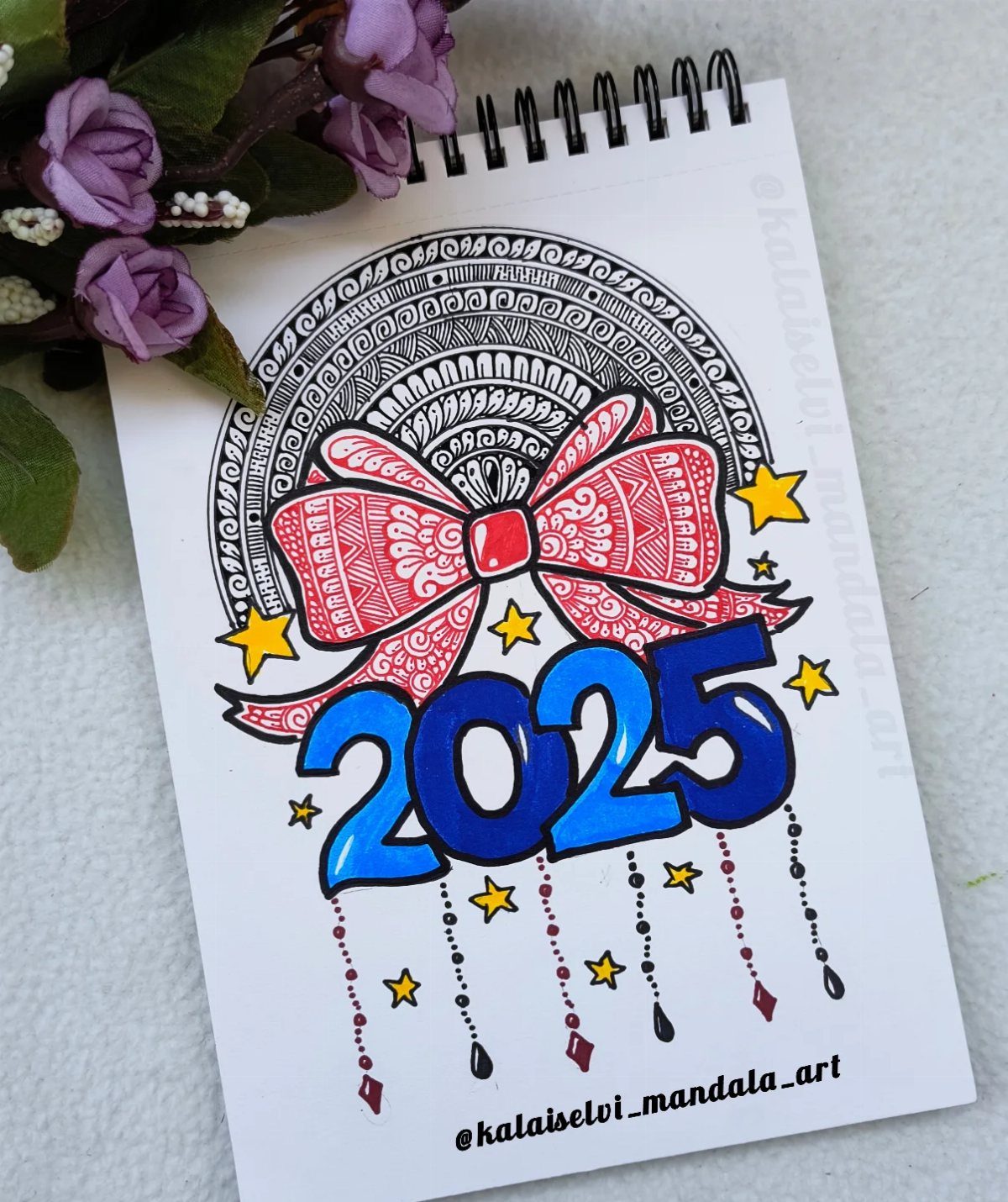 Colored drawing of 2025 with a red bow and mandala art in notebook