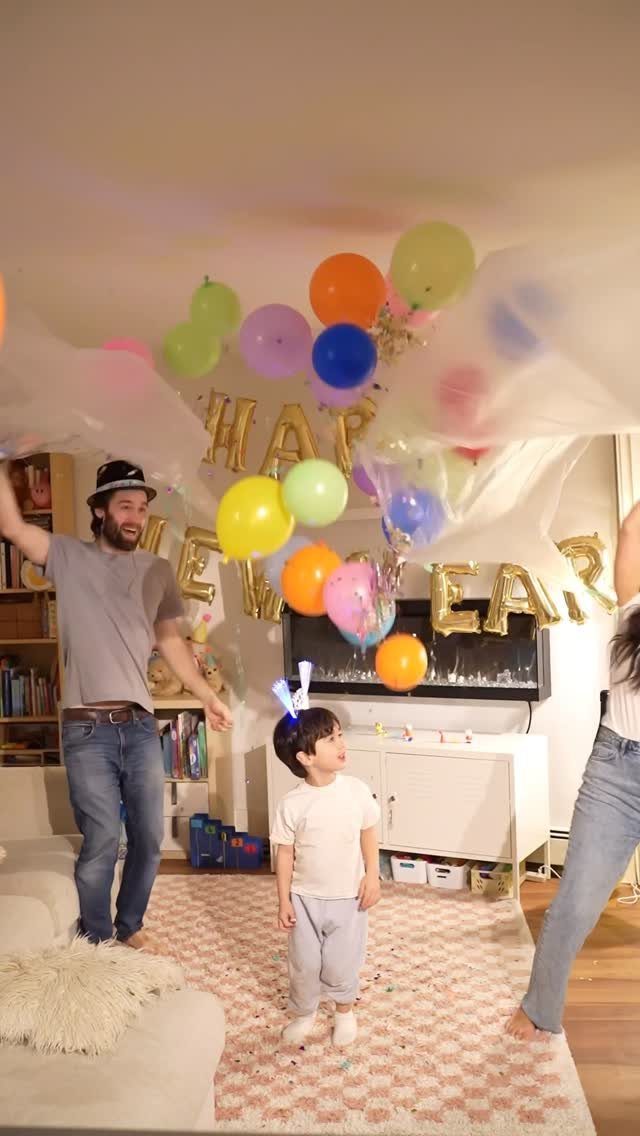 Colorful balloons falling from a ceiling drop over a family celebrating New Year.