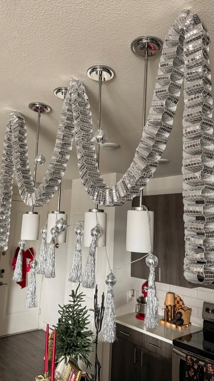 Silver metallic tinsel garlands draped across a ceiling and pendant lights in a kitchen