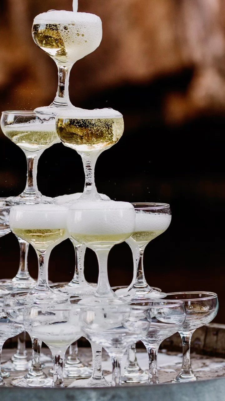 Champagne tower of coupe glasses filled with bubbling sparkling wine and white foam.