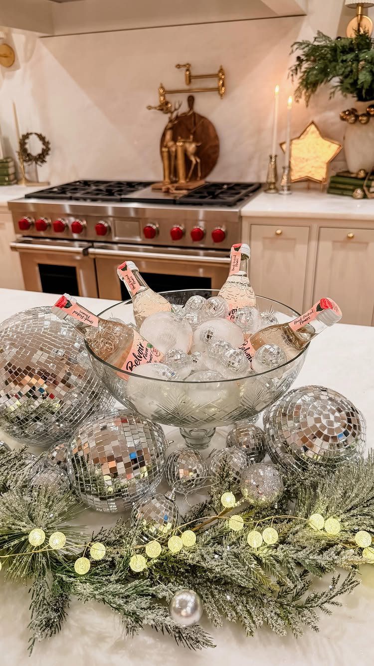 Champagne bottles in ice with disco balls and lighted evergreen garland on countertop