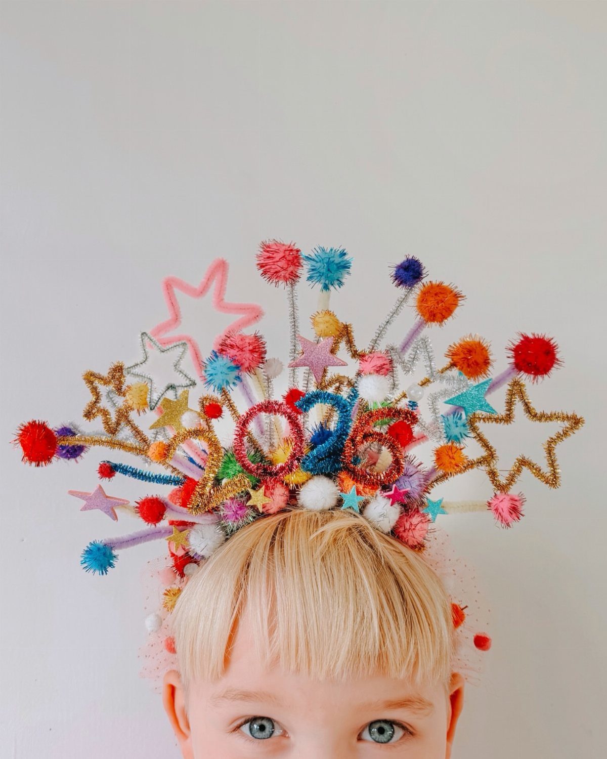 Child wearing a colorful New Year's headband with stars and 2026 numbers.