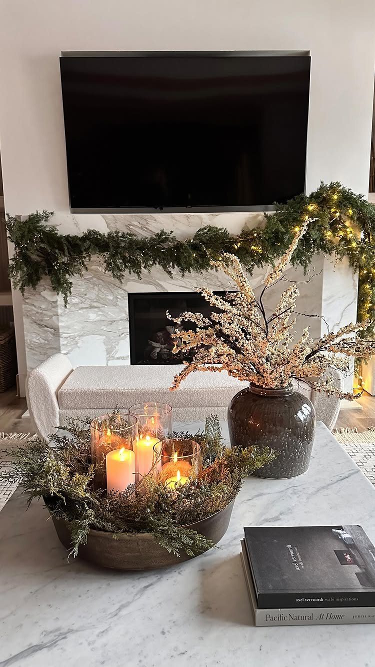 Bowl with lit candles and greenery centerpiece on a white marble coffee table