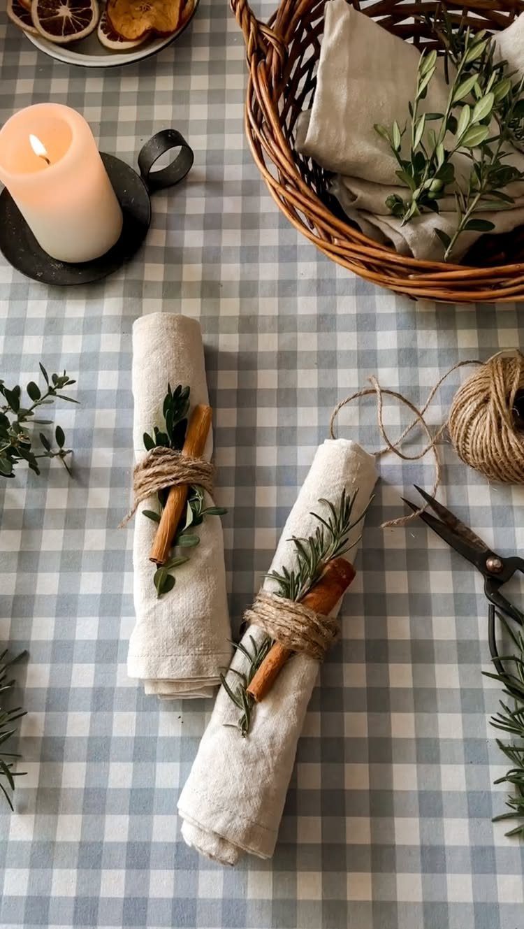 Rolled linen napkins tied with twine, cinnamon sticks, and fresh green herbs.