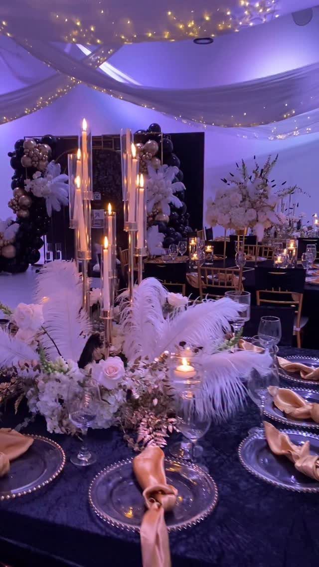 Black tablecloth with gold plates, gold napkins, and a tall gold candelabra centerpiece.