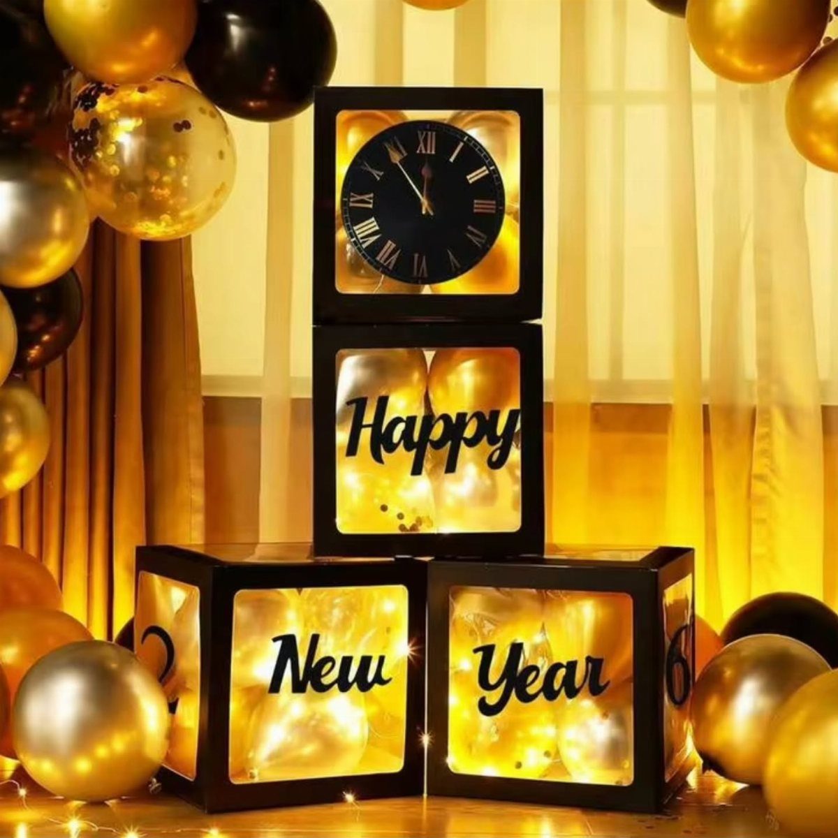 Black light boxes with a clock and Happy New Year text among gold balloons.