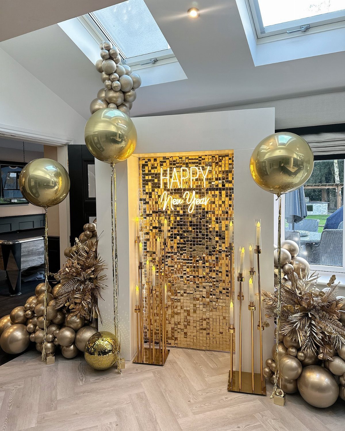 Gold balloons and a shimmering Happy New Year backdrop in a modern room.