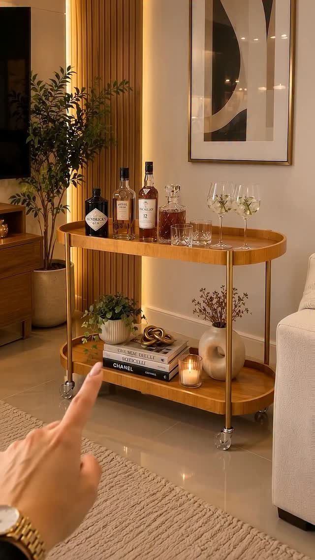 Gold bar cart with liquor bottles, glassware, and decorative books in a living room.