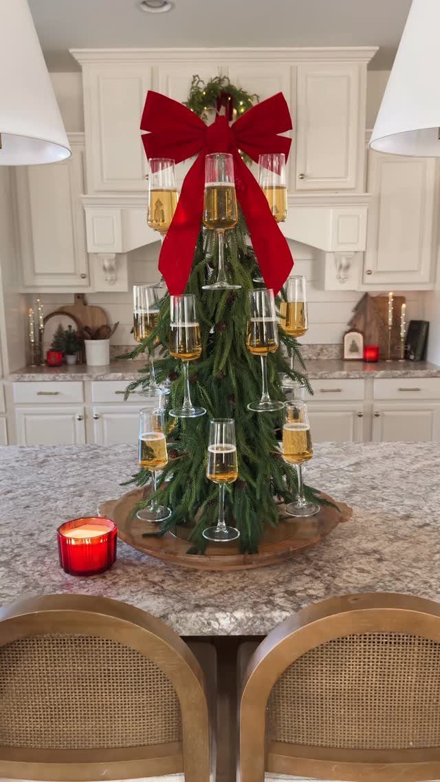 Small evergreen tree with a red bow and champagne flutes on a kitchen counter.