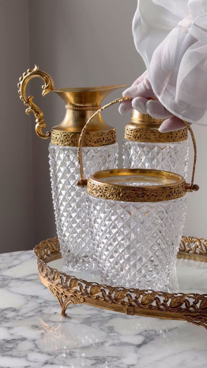 Gold ornate tray with crystal glassware on a white marble tabletop.