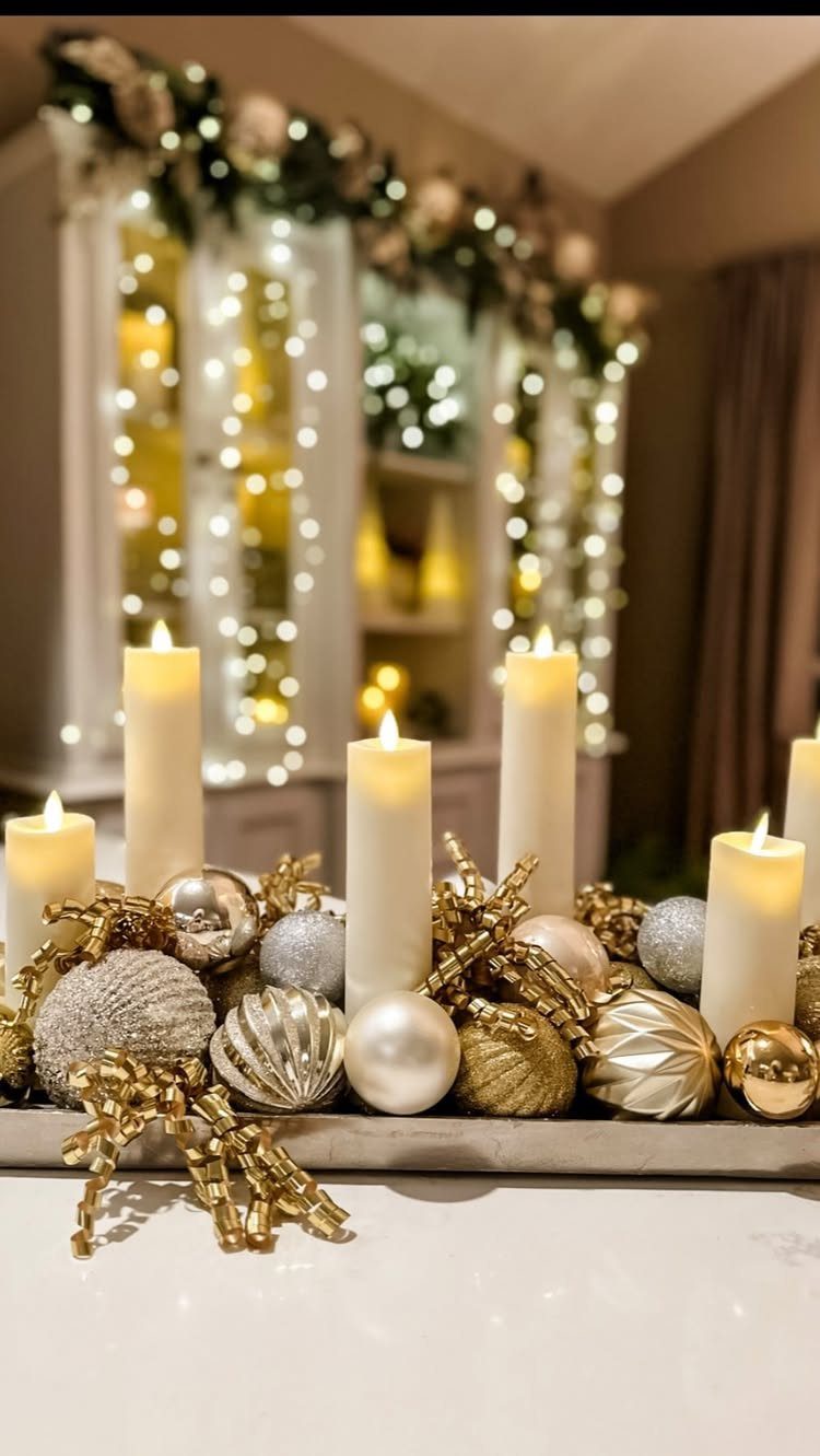 White pillar candles and gold and silver ornaments on a decorative tabletop tray.