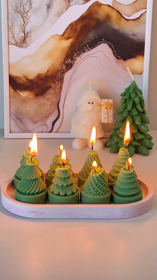 Green tree-shaped candles of different heights arranged on a pink oval tray.