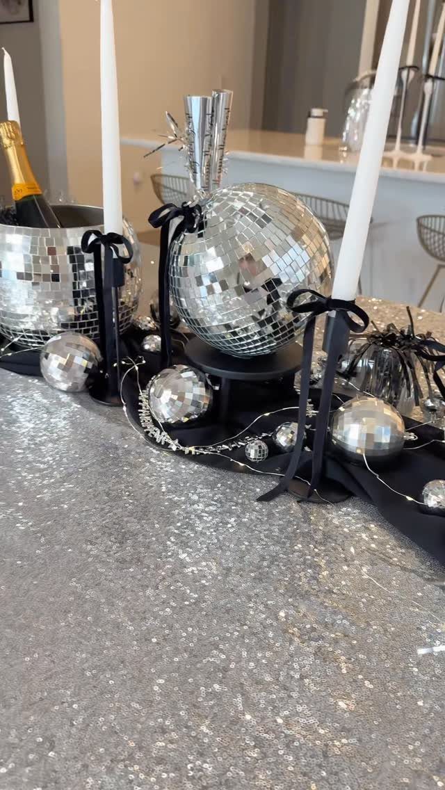 Silver disco balls of various sizes arranged as a centerpiece on a sequined table.