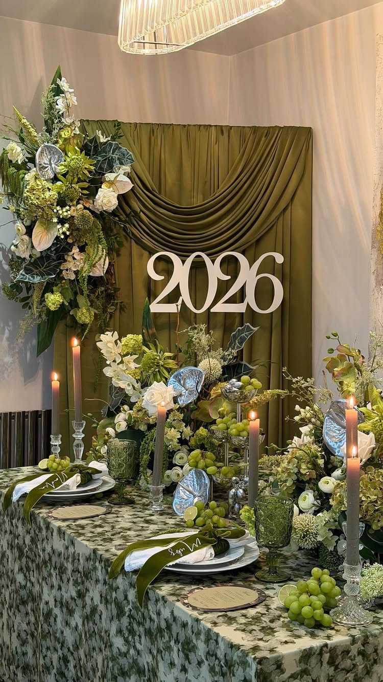 Festive New Year's table setting with green decor, candles, and 2026 backdrop.