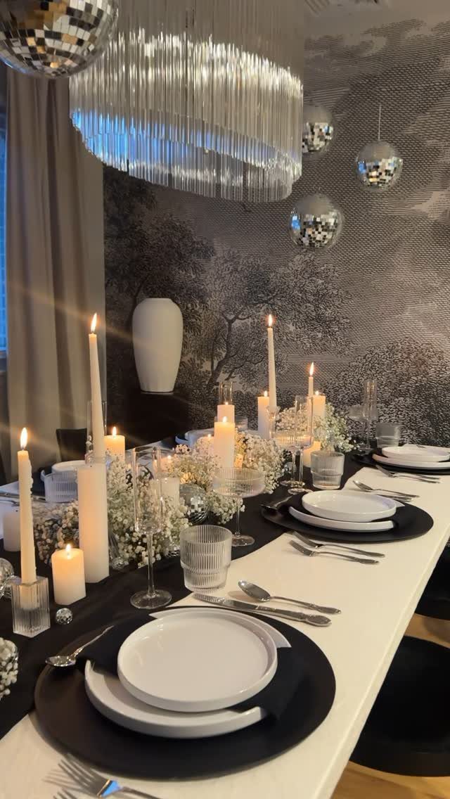 Elegant table setting with black placemats, white plates, white candles, and baby's breath.