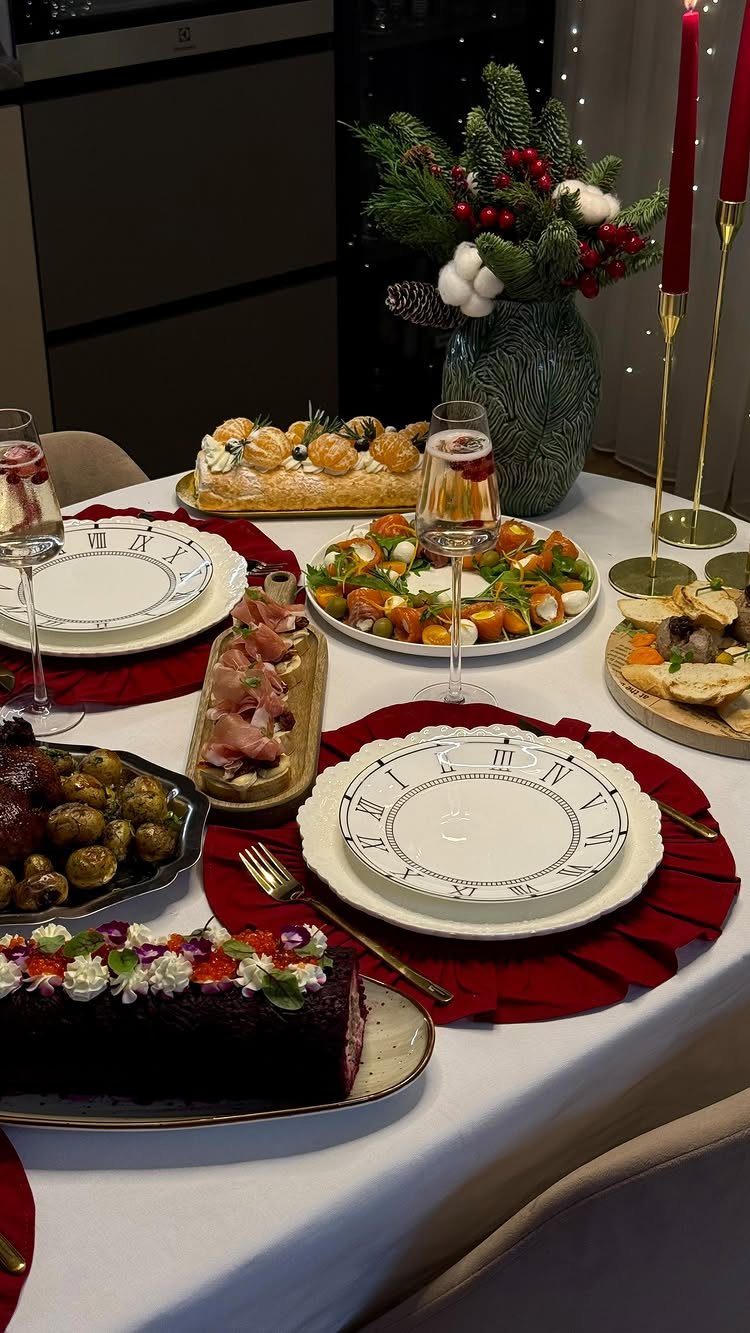 Festive dinner table with red placemats, white plates, appetizers, and red candles.