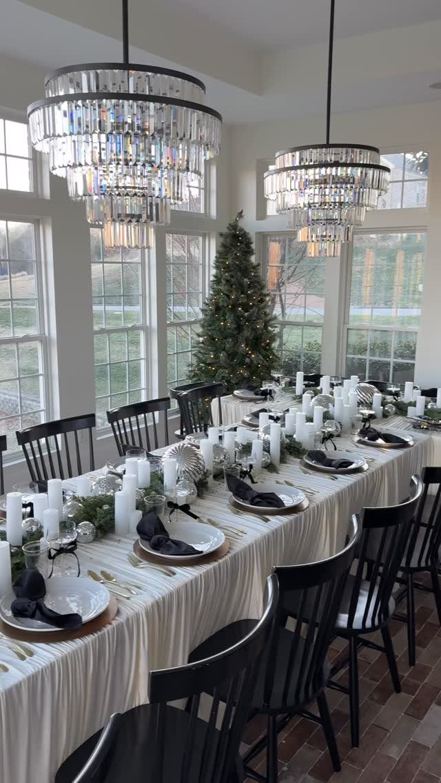 Elegant dining table set with white plates, black napkins, and silver holiday decorations.