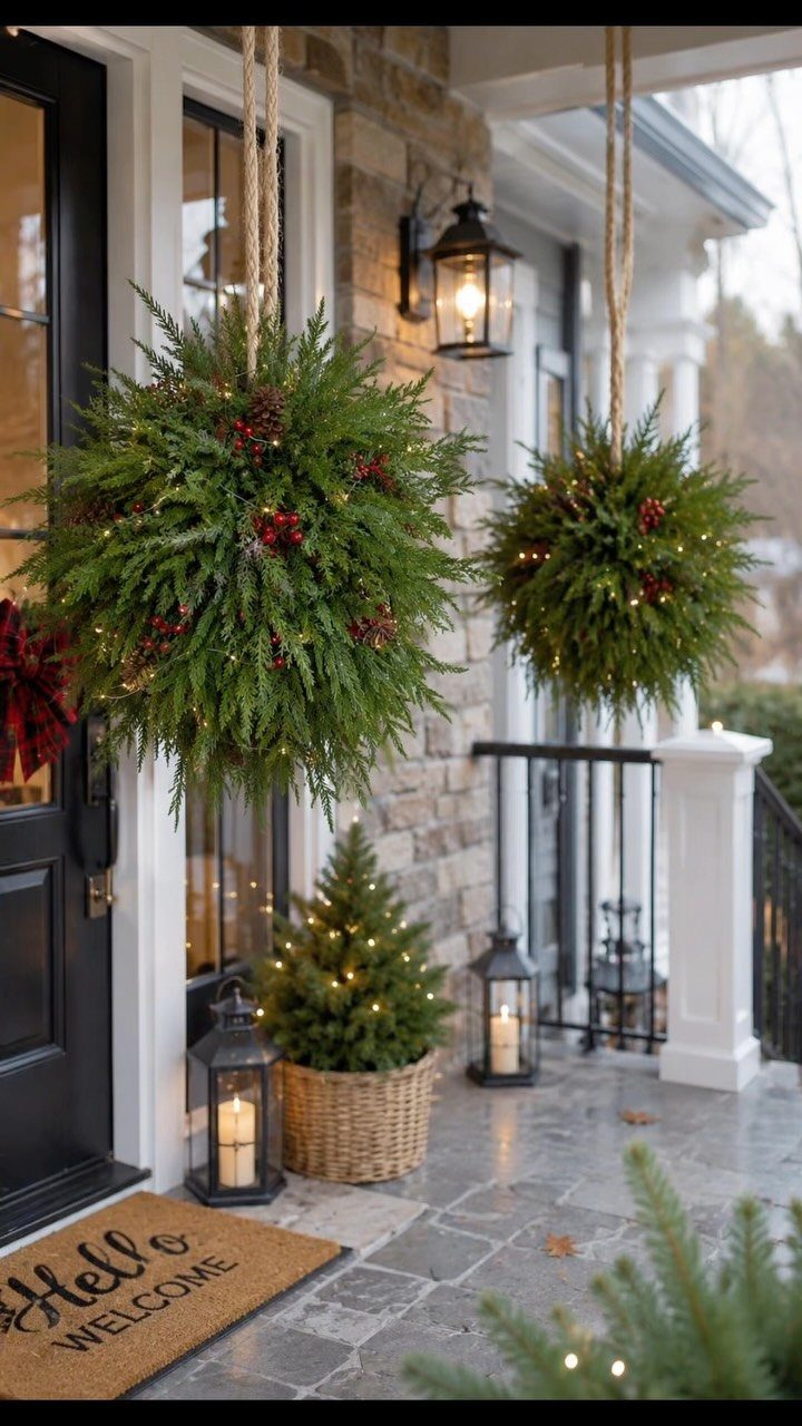 Evergreen hanging spheres and a small potted tree decorating a stone house porch.
