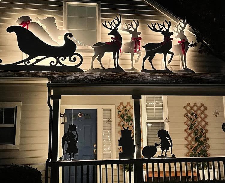 Backlit silhouette of Santa in his sleigh pulled by reindeer on a roof