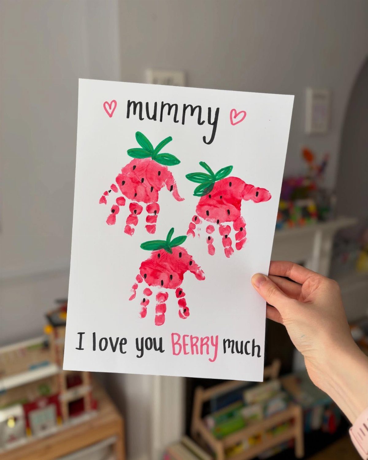 Hand-painted strawberry handprints on a card for Mummy with a berry pun.