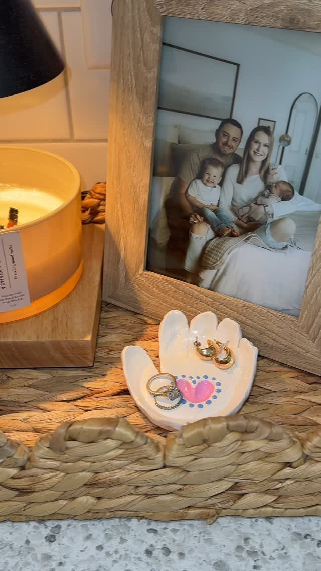 White ceramic hand-shaped jewelry dish with a pink heart on a woven tray