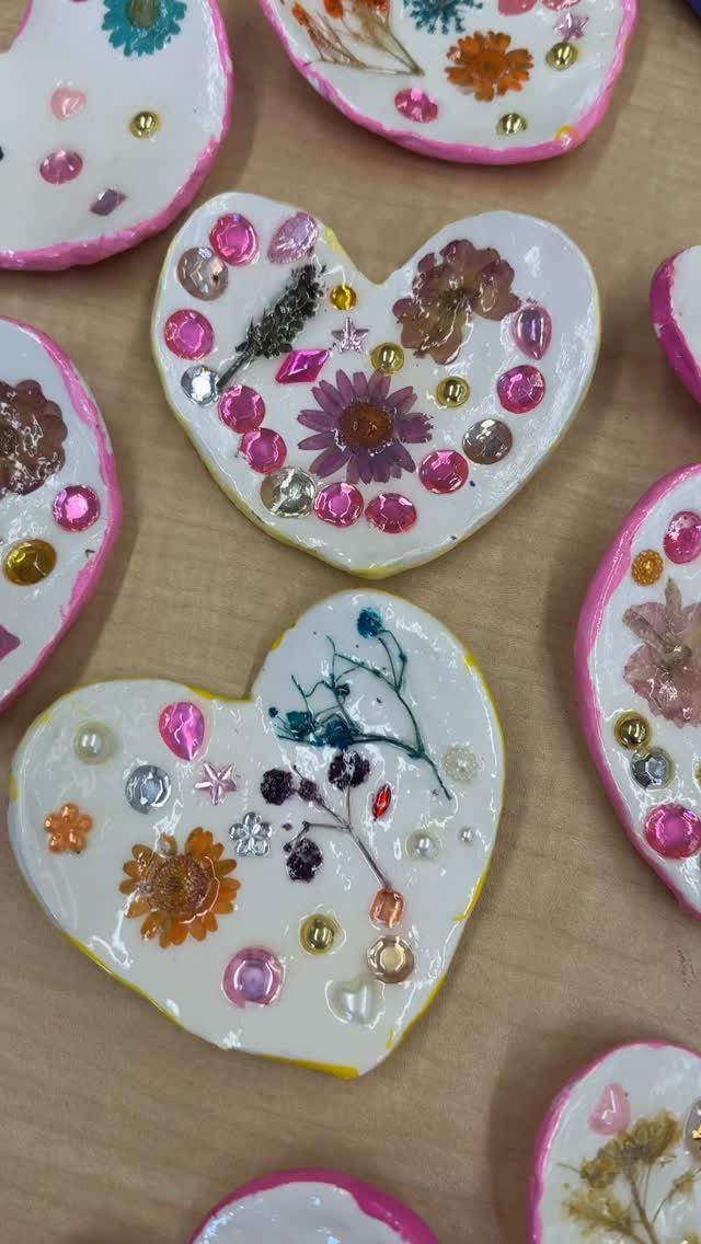 Heart-shaped white ornaments decorated with pressed dried flowers, sequins, and colorful beads.