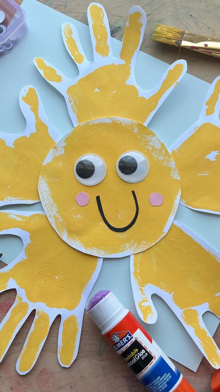 Yellow sun craft with a smiley face and yellow painted handprint rays.