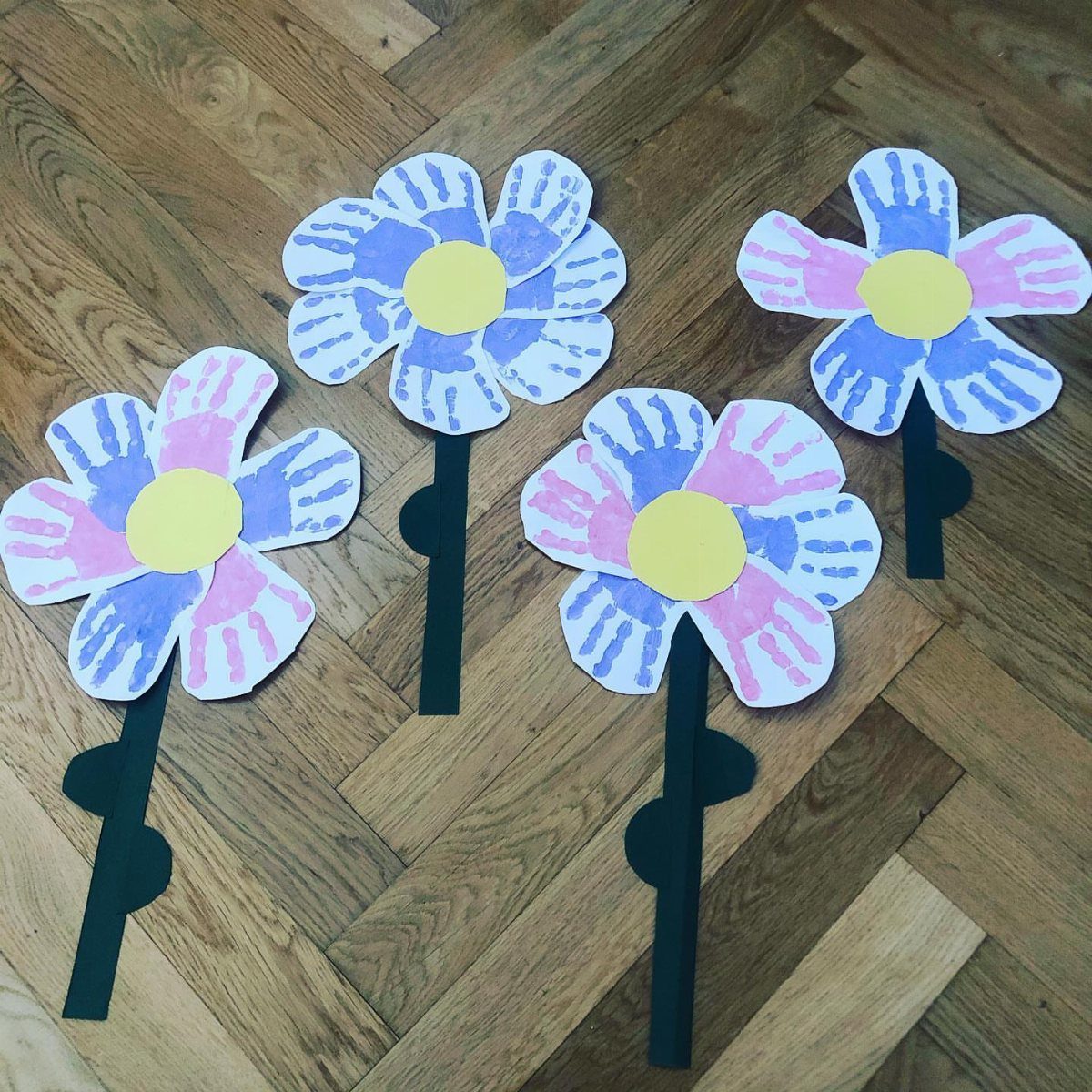 Handmade paper flowers with blue and pink petals on a wooden floor