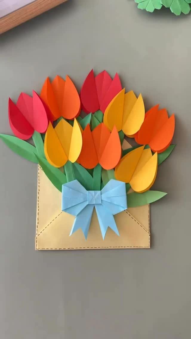 Colorful paper tulips in a yellow envelope with a blue bow craft.