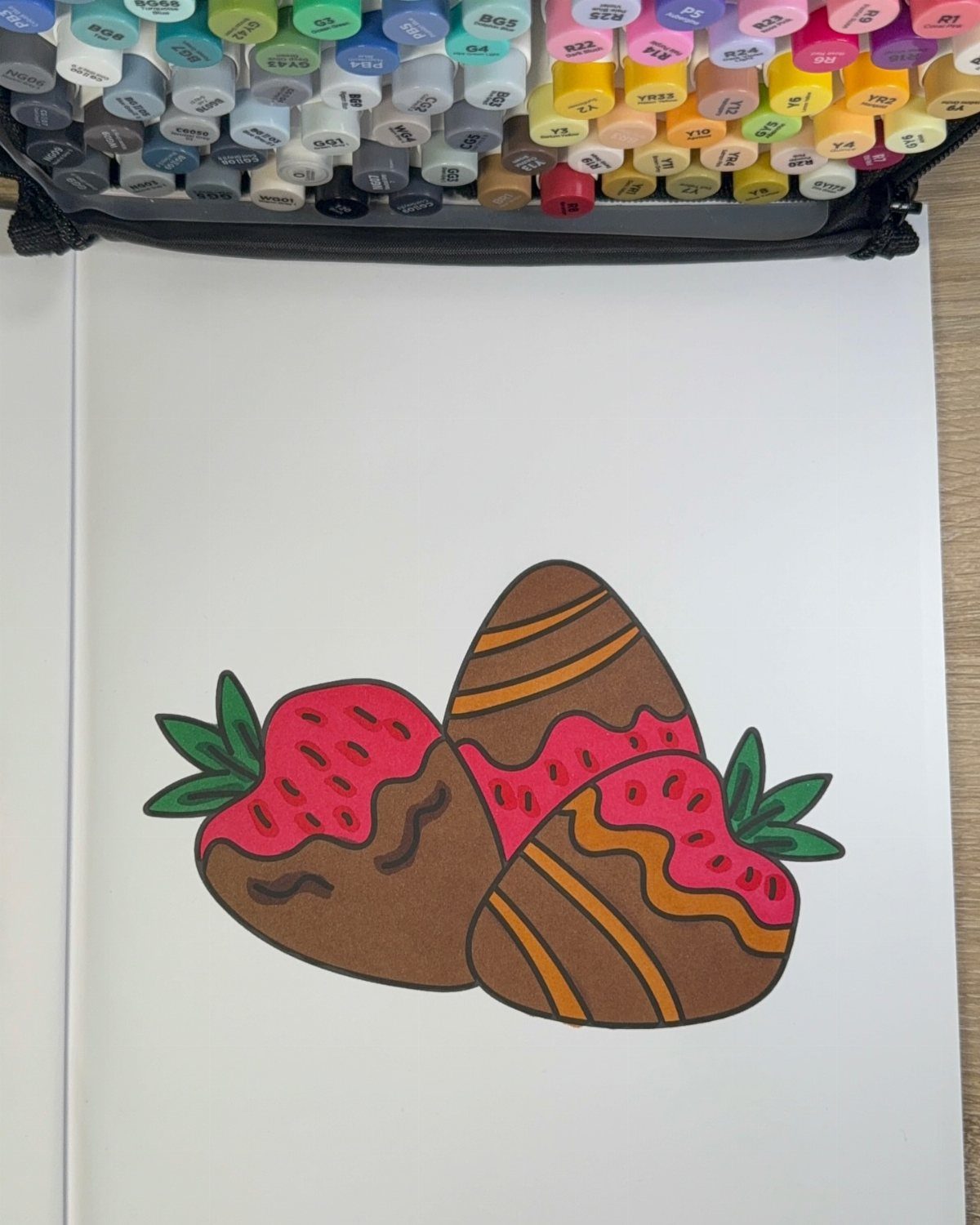 Chocolate covered strawberries drawing on white paper with colorful markers above