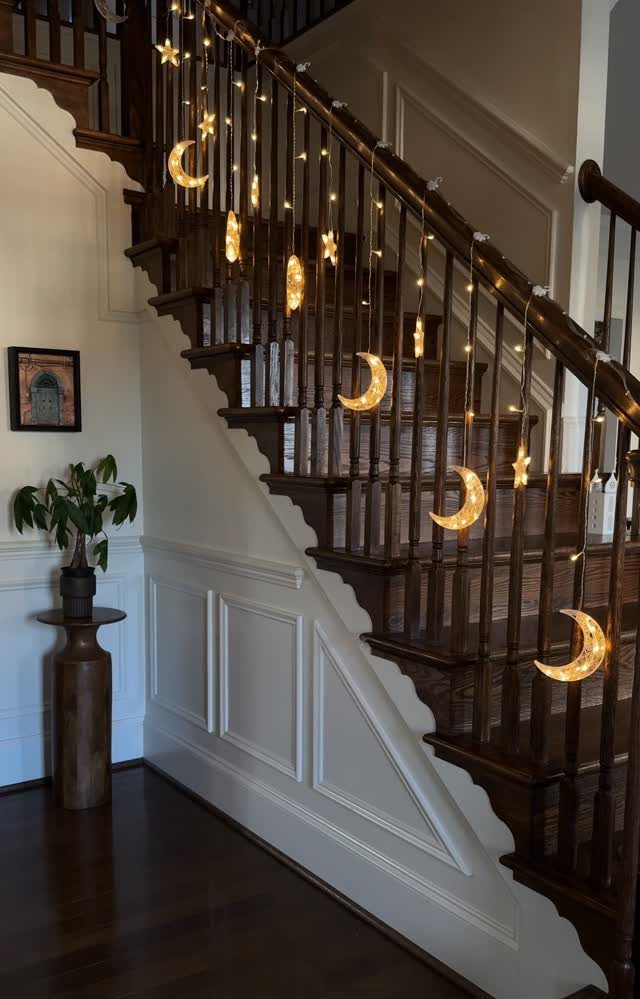 Crescent moon and star string lights hanging from a wooden staircase railing.