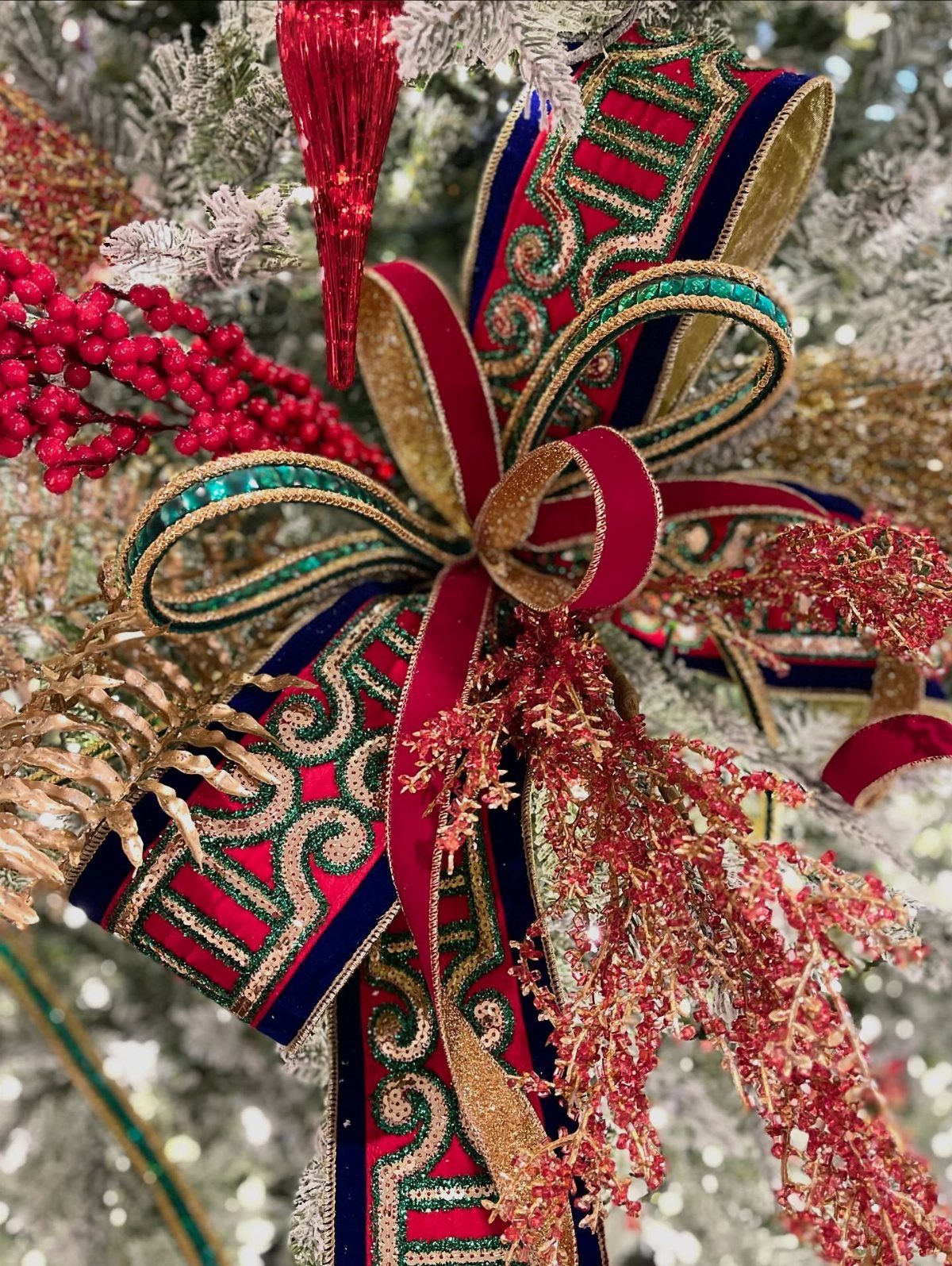 Ornate red and gold wired ribbon bow on a flocked Christmas tree