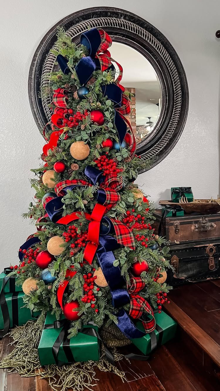 Christmas tree decorated with contrasting red, blue, and plaid ribbons and red ornaments.
