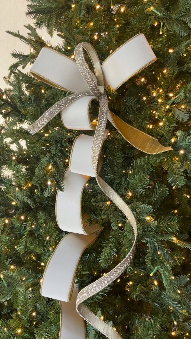 White and silver ribbons layered and tied in a bow on a Christmas tree