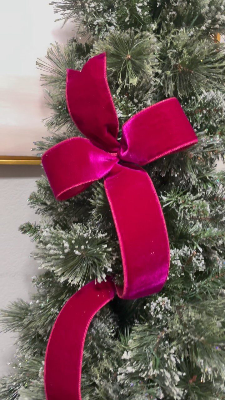 Magenta velvet ribbon tied in a bow on a frosted Christmas tree branch