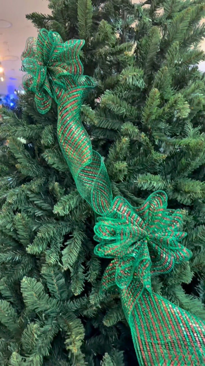 Green and red striped ribbon spiraling down a green Christmas tree with bows.