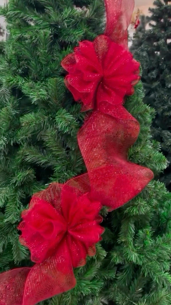 Red shimmering wired ribbon with large bows woven through green Christmas tree branches