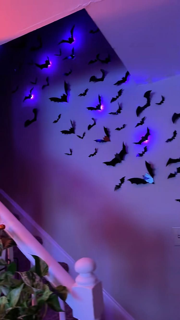 Black bat silhouettes on a wall illuminated by purple and blue light.