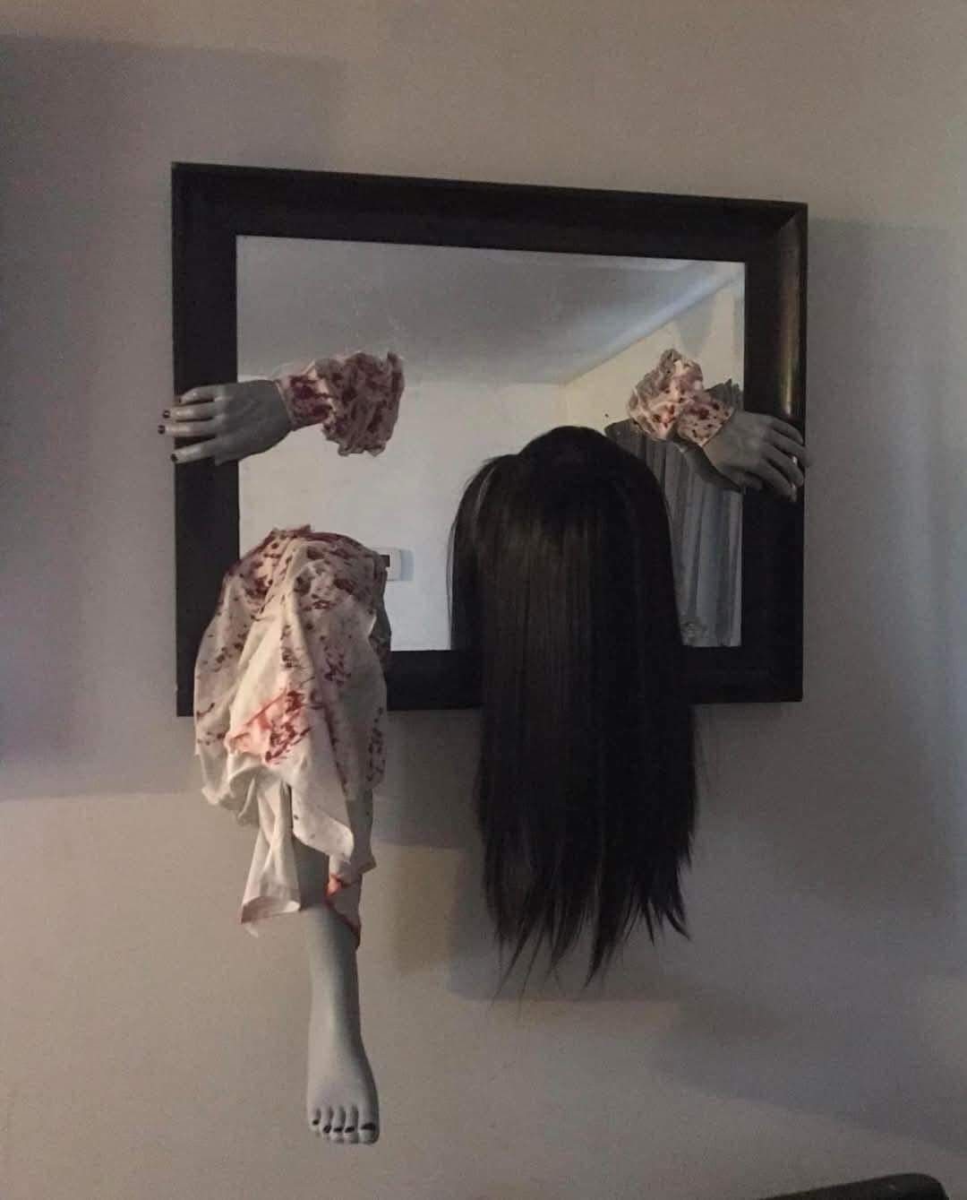 Spooky mirror decoration with mannequin limbs and black hair emerging from the frame.