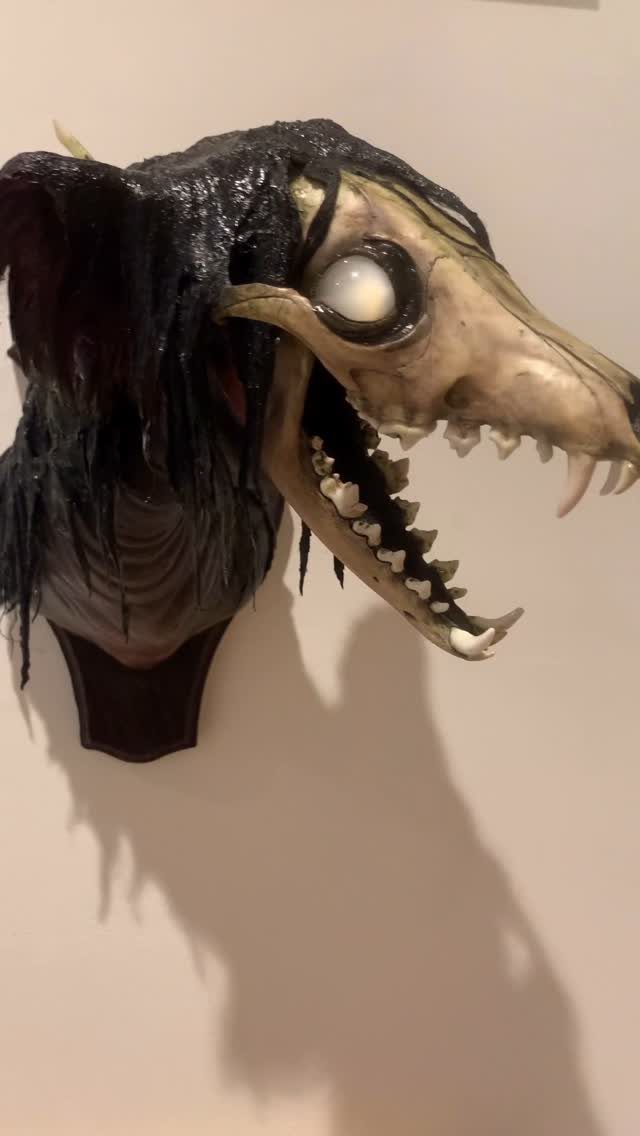 Monster head decoration with sharp teeth and glowing eye mounted on a wall