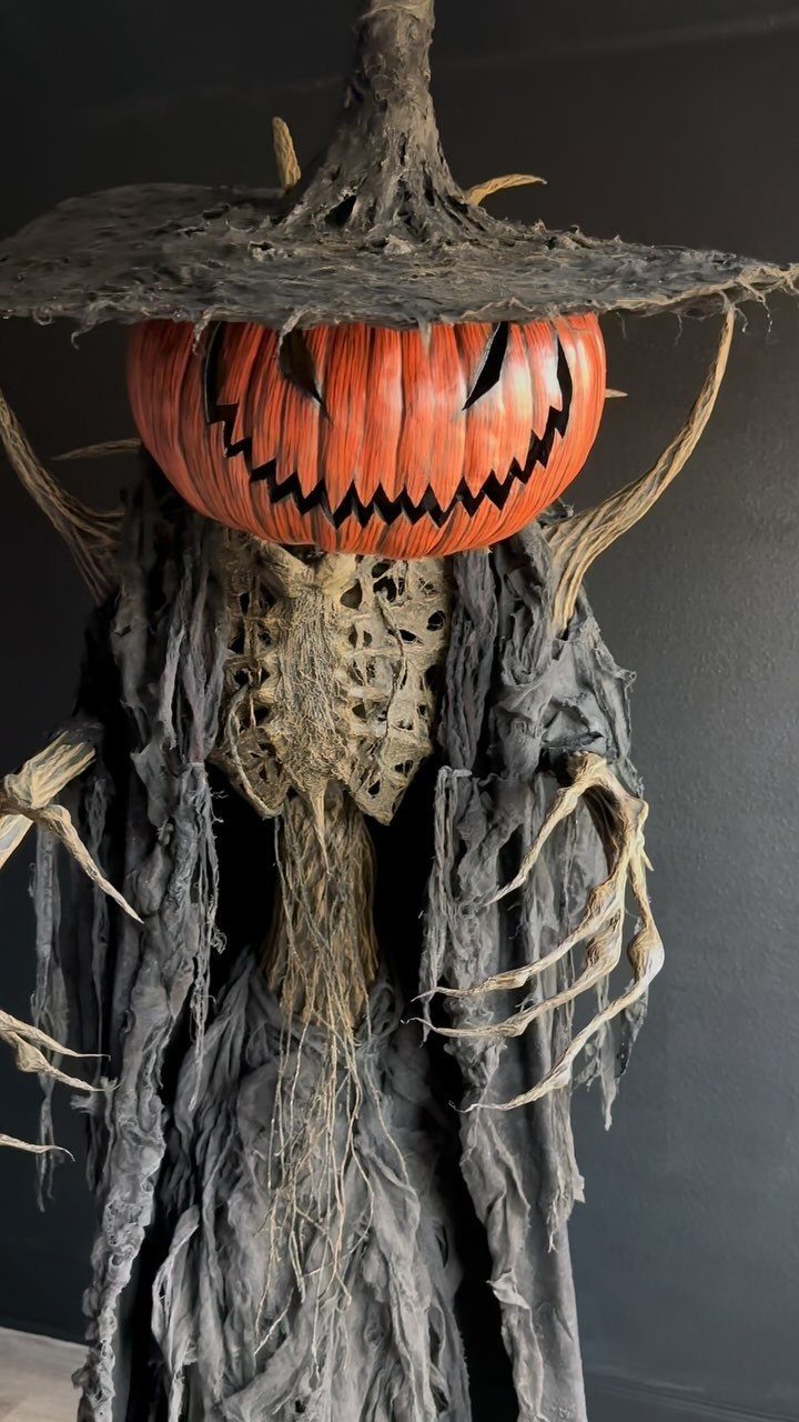 Scary pumpkin-headed figure wearing a tattered witch hat and shredded grey clothing.