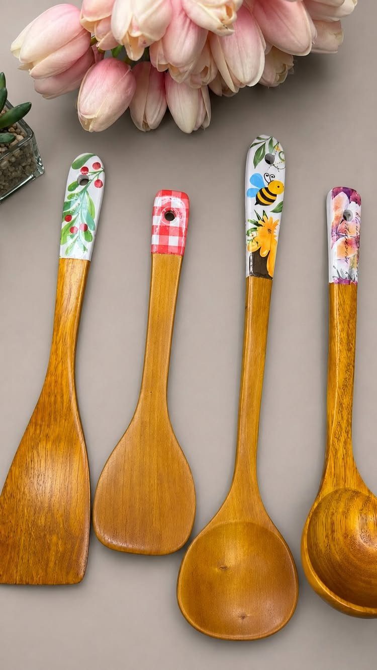 Wooden kitchen utensils with decorative floral and patterned handle wraps next to pink tulips.