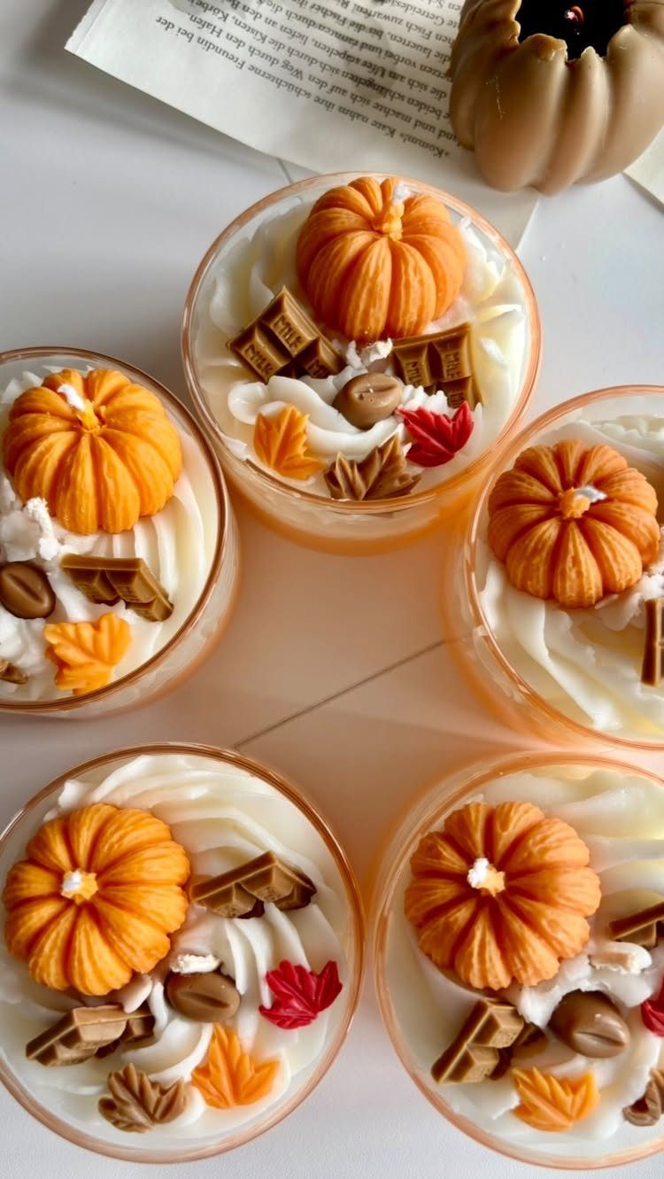 Autumn themed scented candles with pumpkin and chocolate wax decorations in glass jars